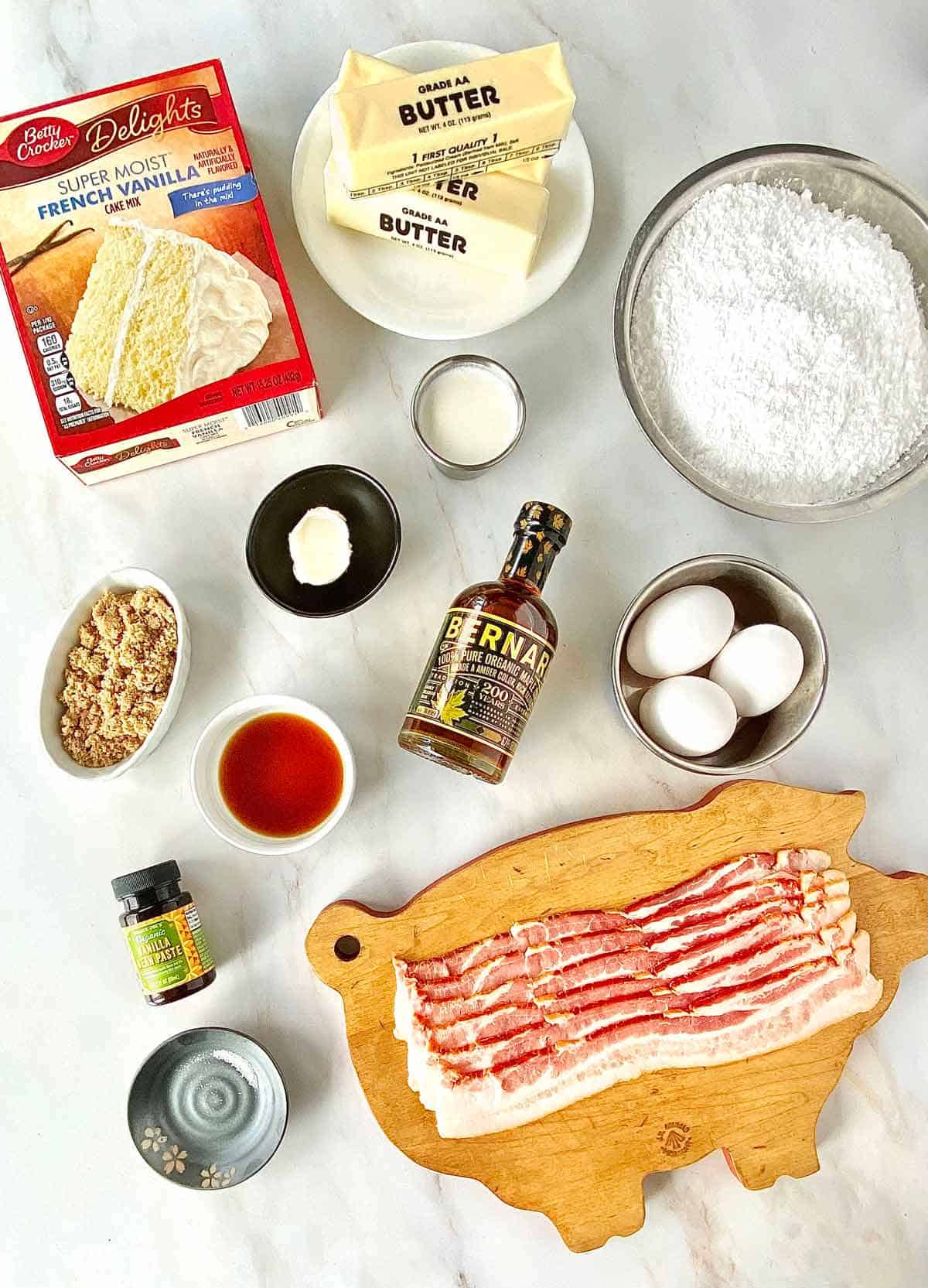Cake mix, butter, eggs, bacon, powdered sugar, and all the ingredients to make Maple Bacon Cupcakes.