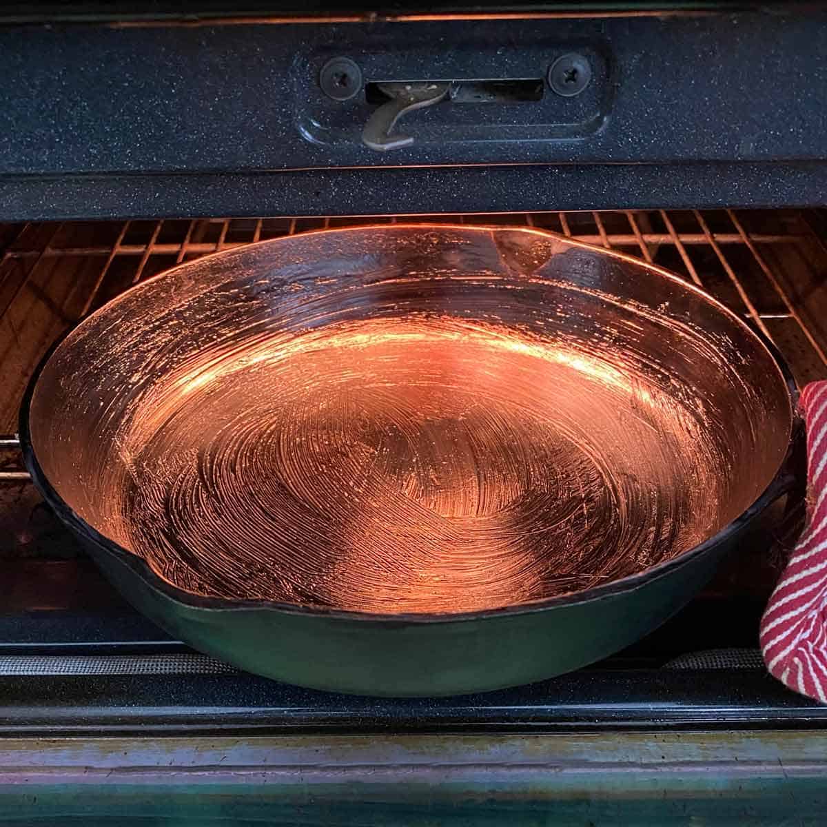 Sliding a cast iron skillet coated with a thin layer of bacon grease into a preheated oven.