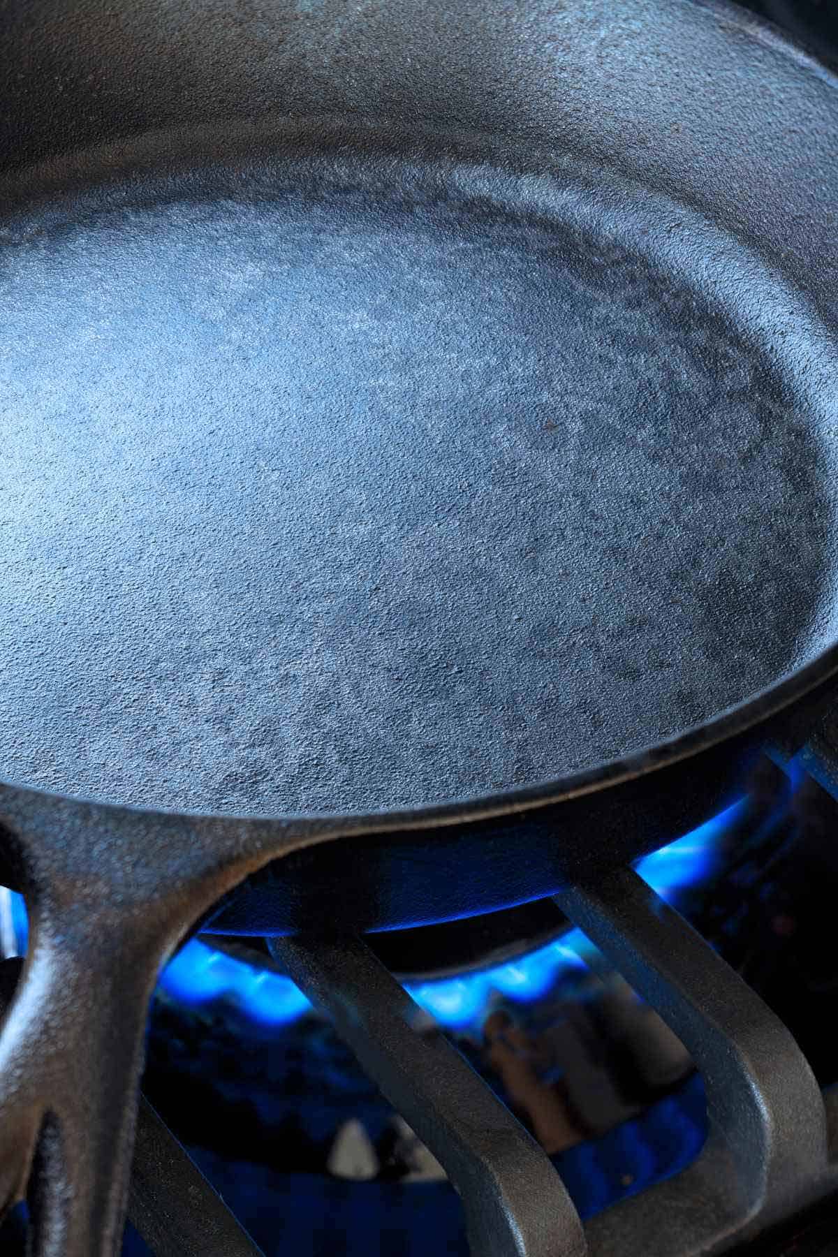Heating a cast iron skillet over a low flame on a gas stove.