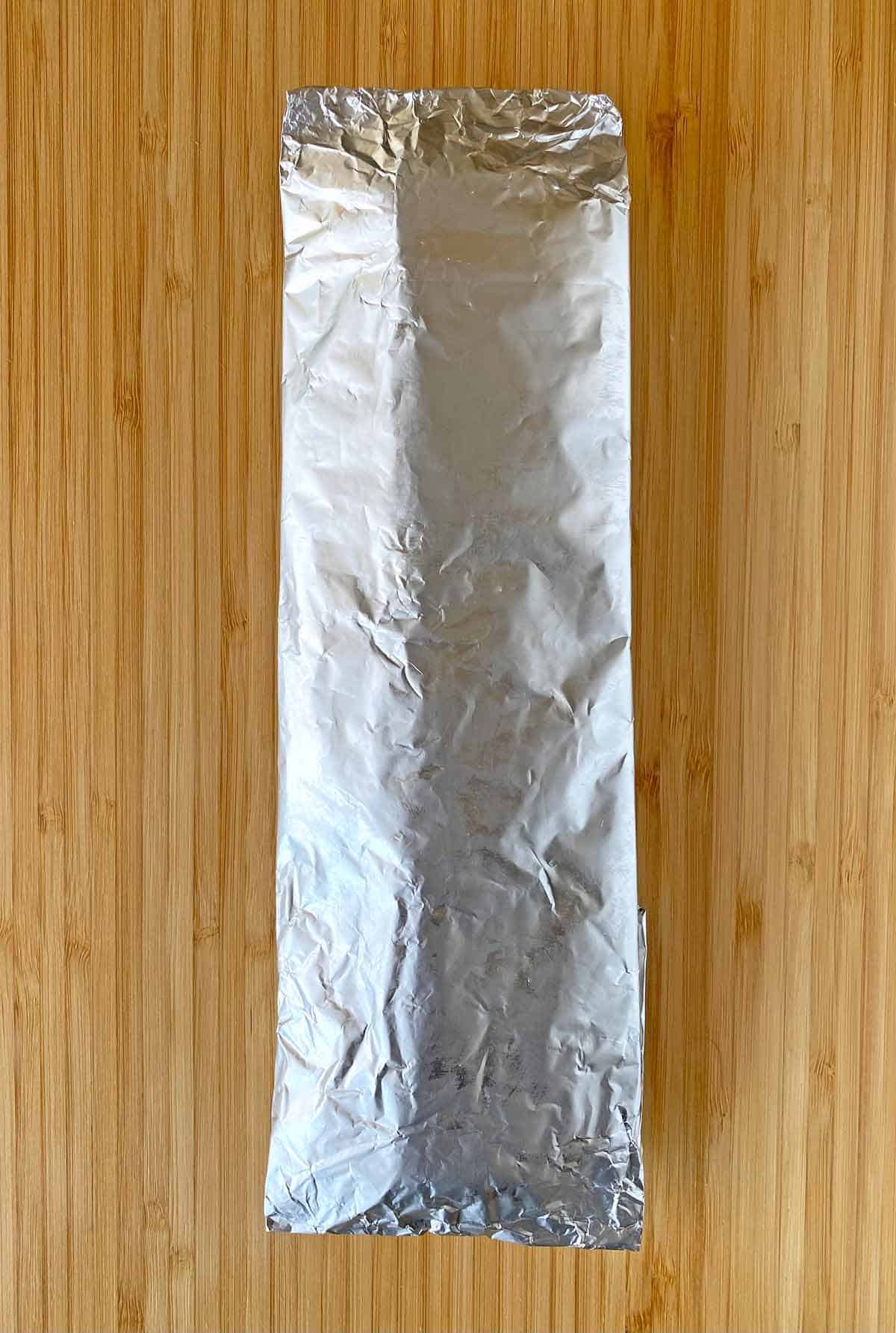 A foil wrapped package of uncooked bacon.