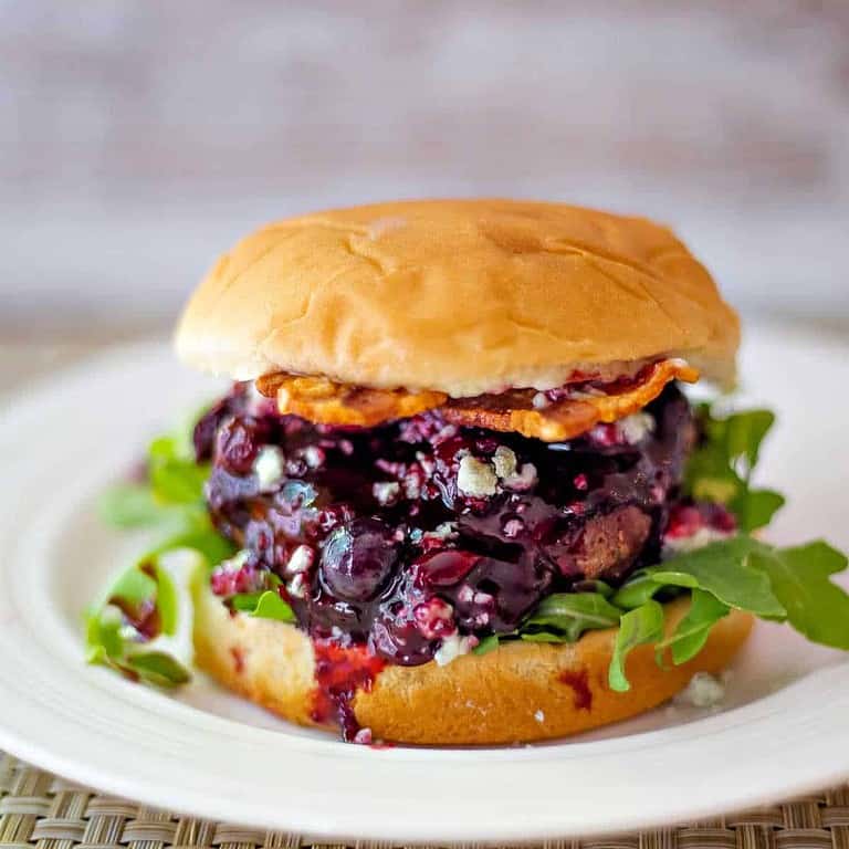A hamburger with bacon and blueberry sauce.