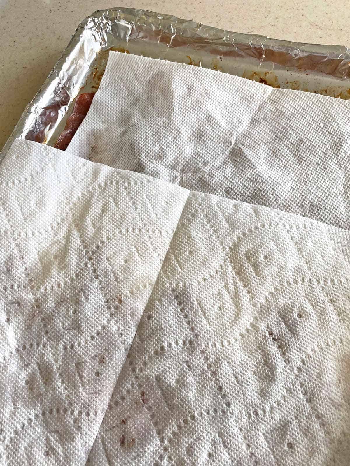 Blotting excess grease from crack bacon with paper towels.