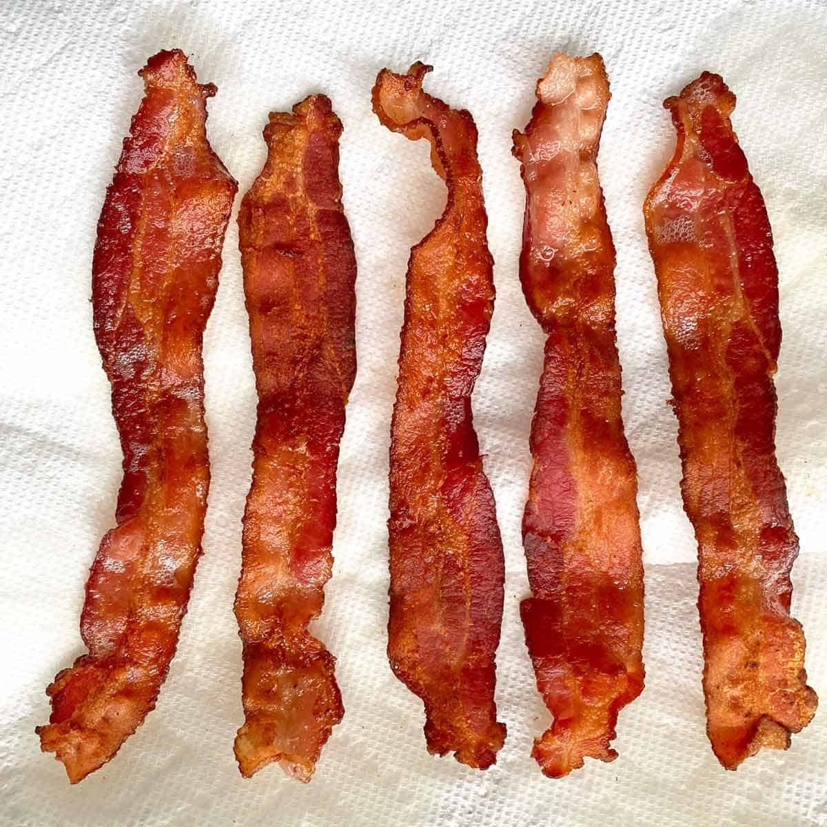 5 strips of cooked bacon draining on paper towels.