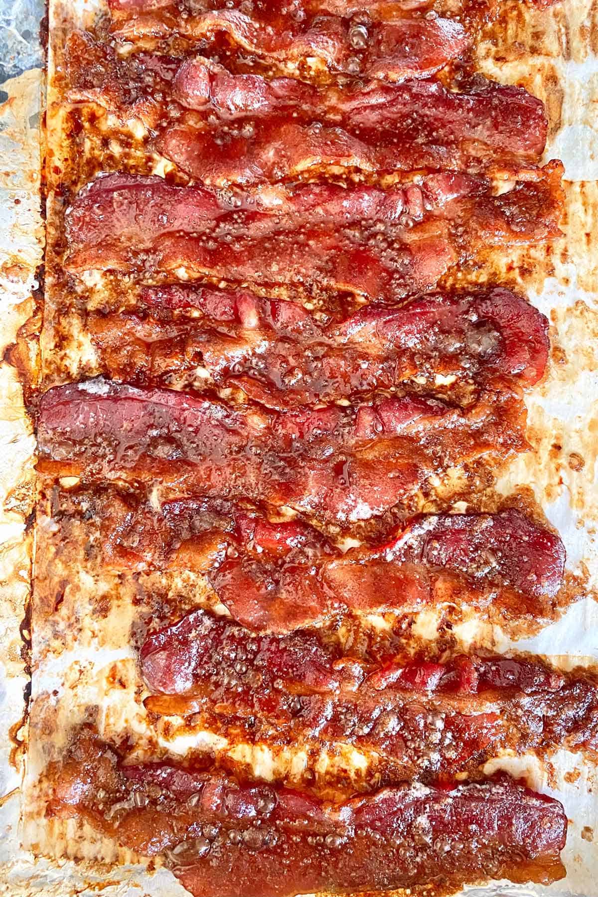 Baked crack bacon strips on a baking sheet, hot from the oven.