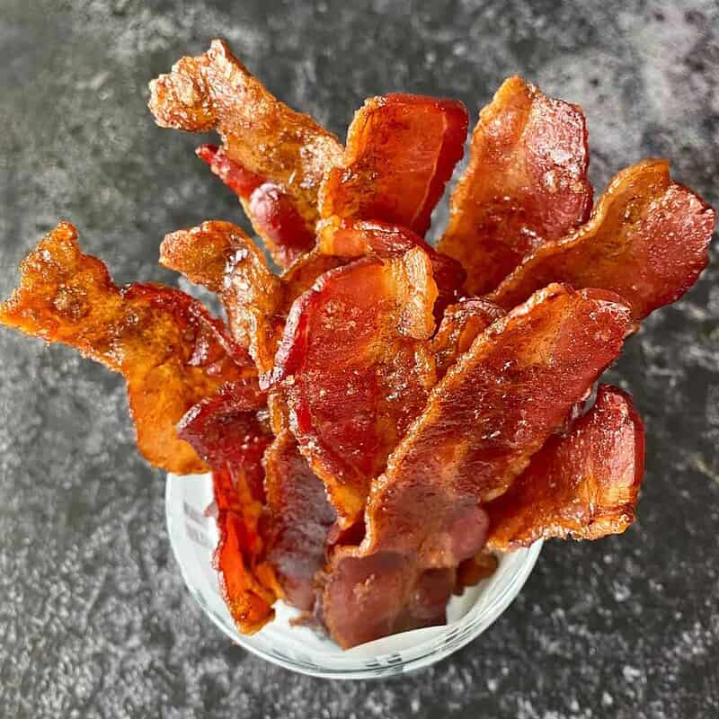 A serving dish with a dozen slices of glazed cracked bacon.