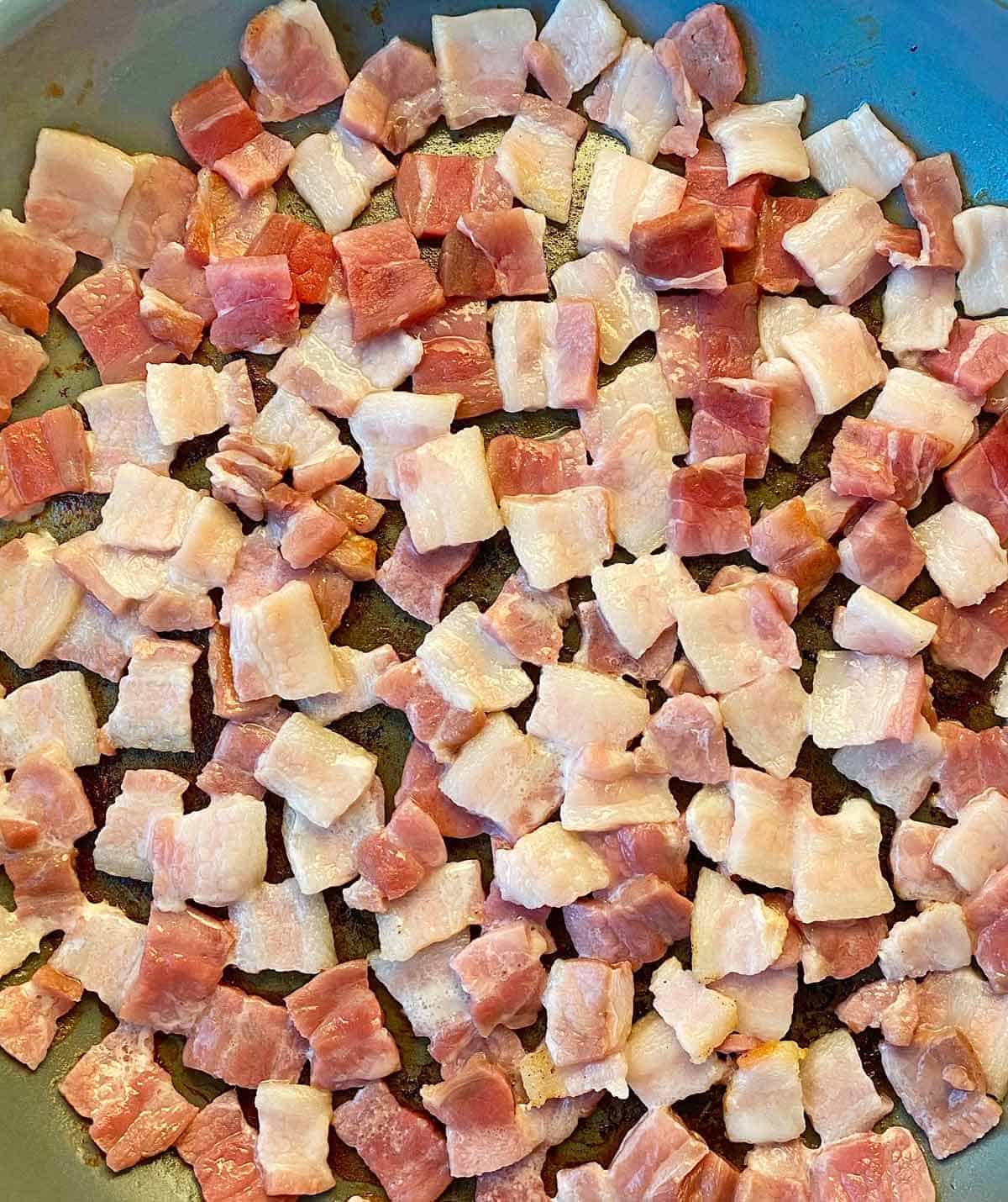 Uncooked chopped bacon squares ready to cook in a nonstick skillet.