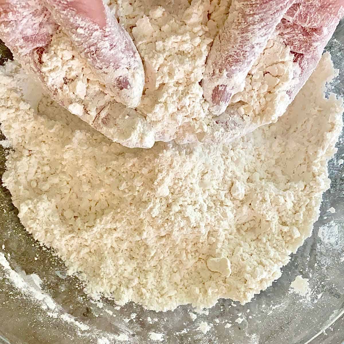 Using hands to blend butter and bacon grease with flour mixture.