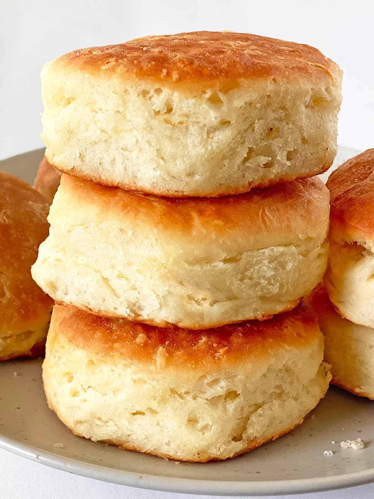 Close up of 3 bacon fat biscuits stacked on a plate.