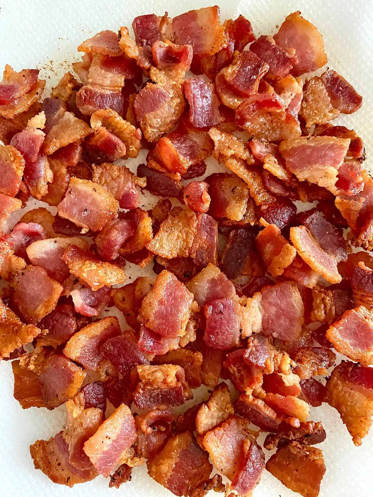 Cooked chopped bacon pieces draining on a paper towel.
