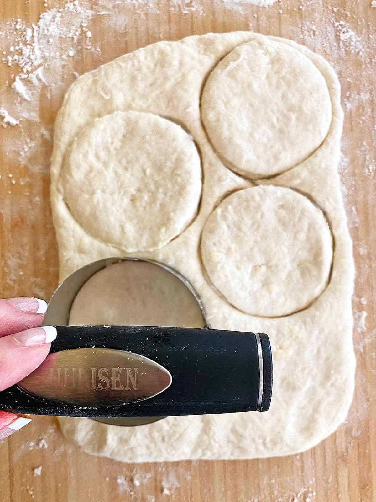 Using a round cutter to cut out biscuits.