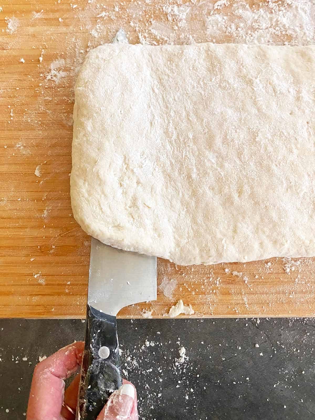 Using a knife to lift the dough and fold it.