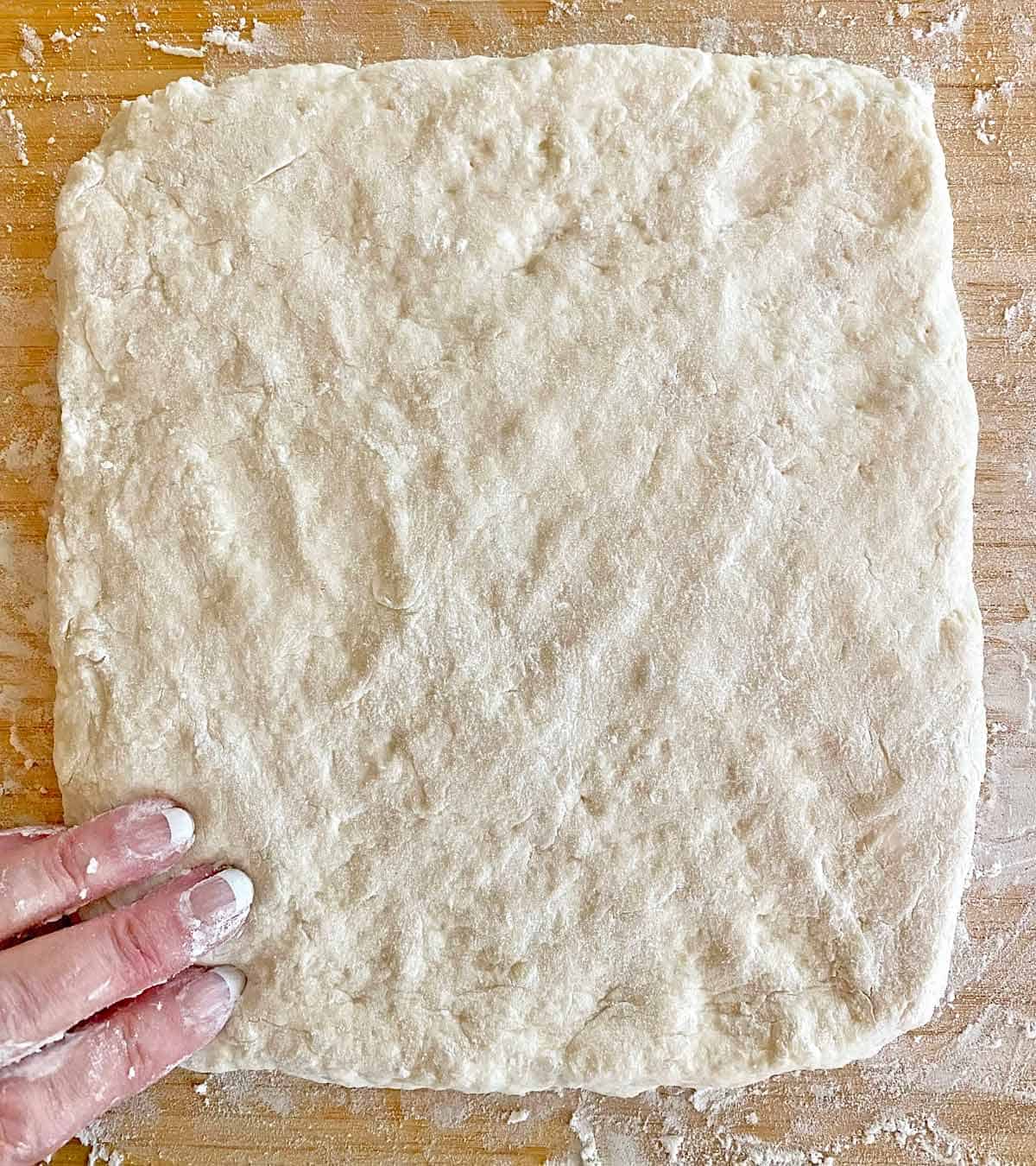 Patting biscuit dough into a rectangle.