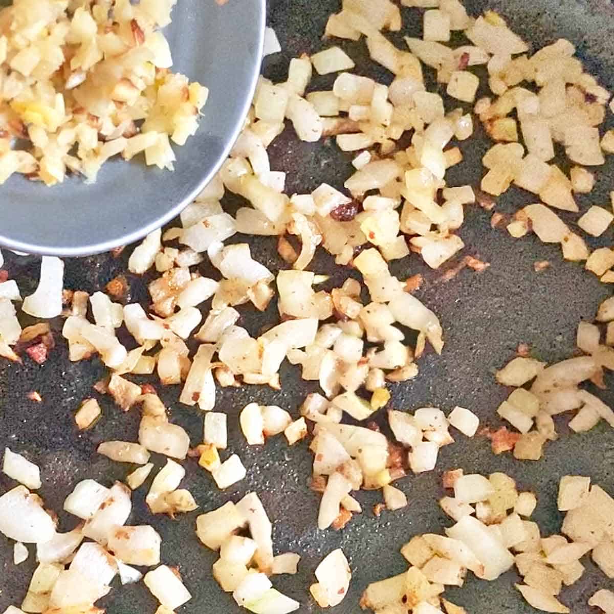 Adding chopped roasted garlic to a pan with caramelized chopped onions.