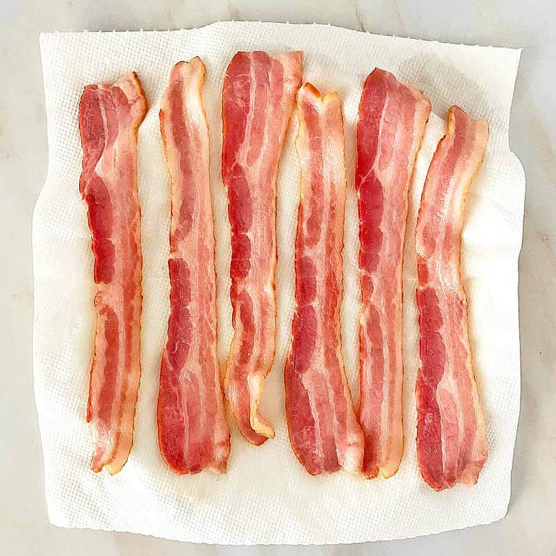 partially cooked bacon on paper towels.