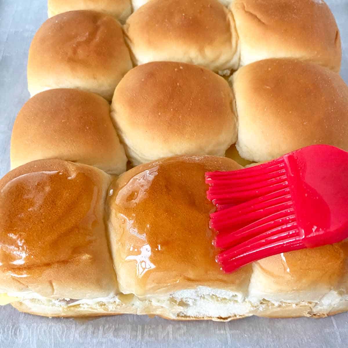 Brushing Hawaiian rolls with the butter Worcestershire mixture.