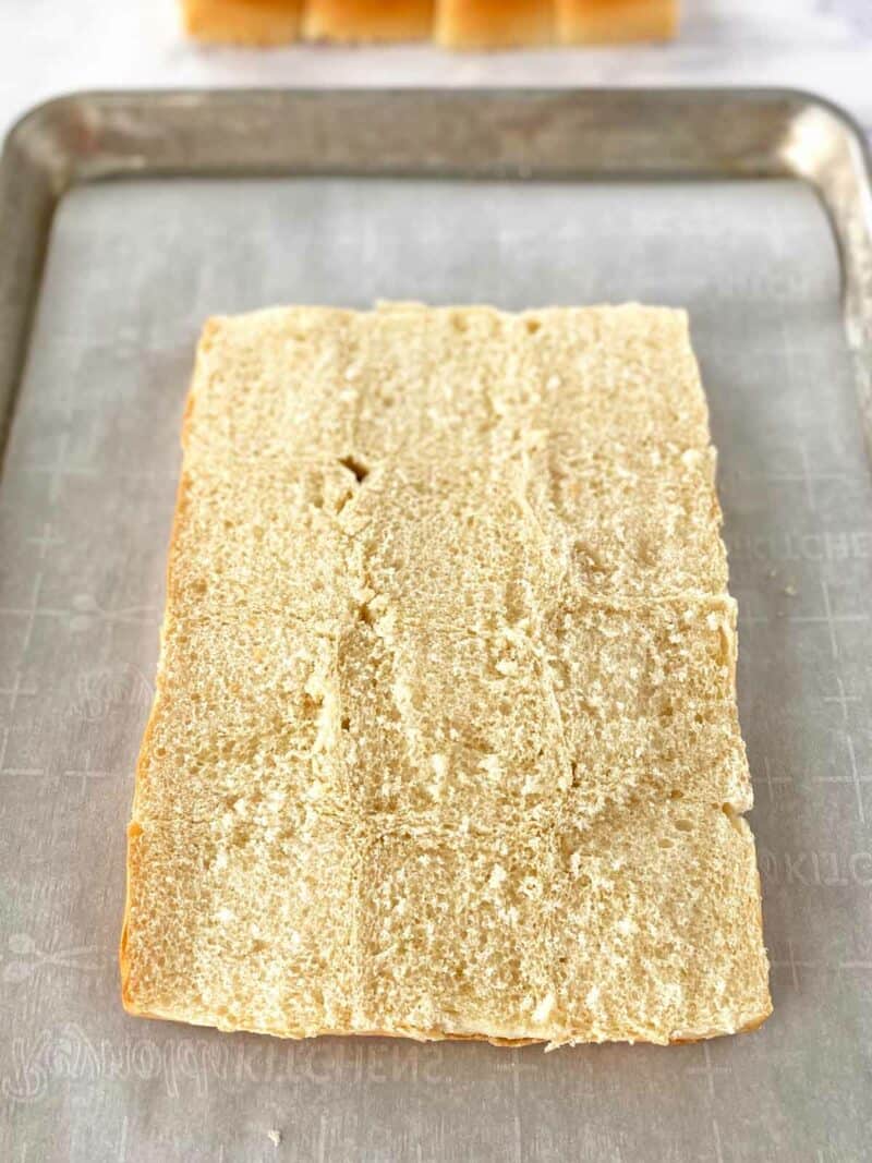 The bottom half of buns on a baking sheet.