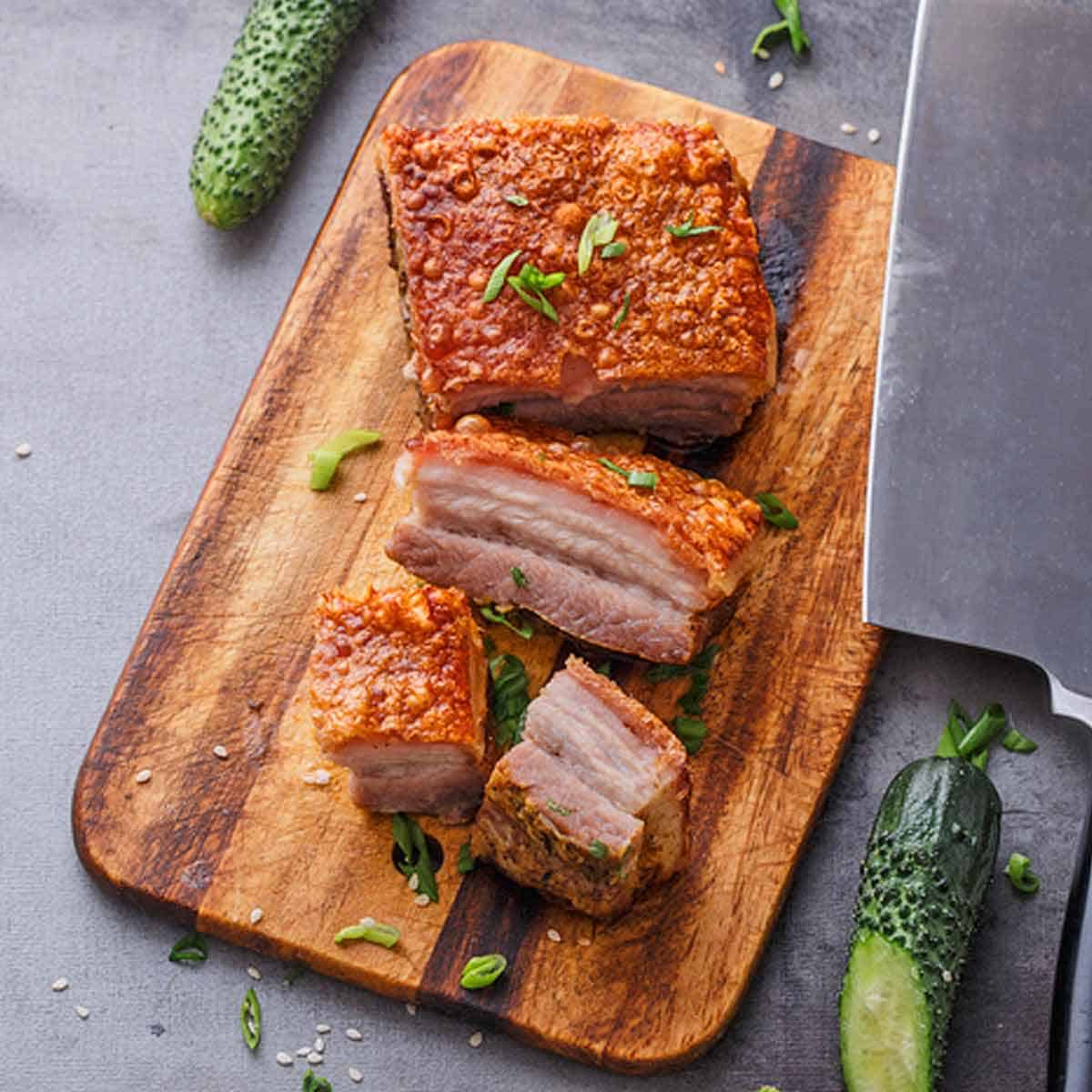 Chinese pork belly and a cleaver on a cutting board.