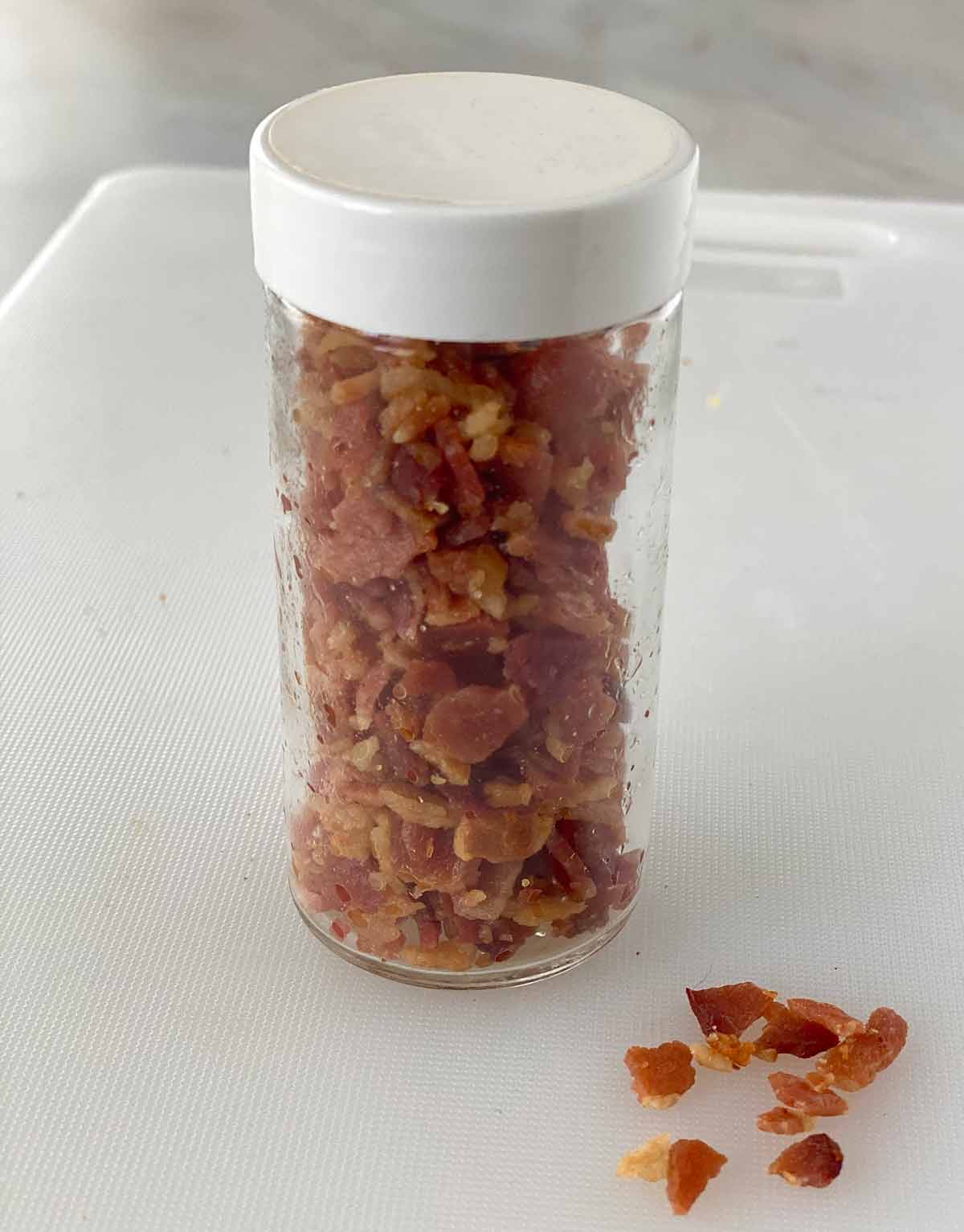 A glass jar filled with bacon crumbles.