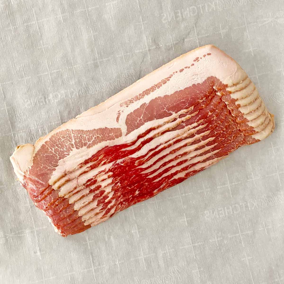 A pound of uncooked bacon on parchment paper.