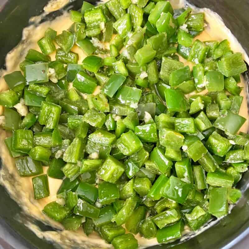 Adding cooked jalapenos to the slow cooker.