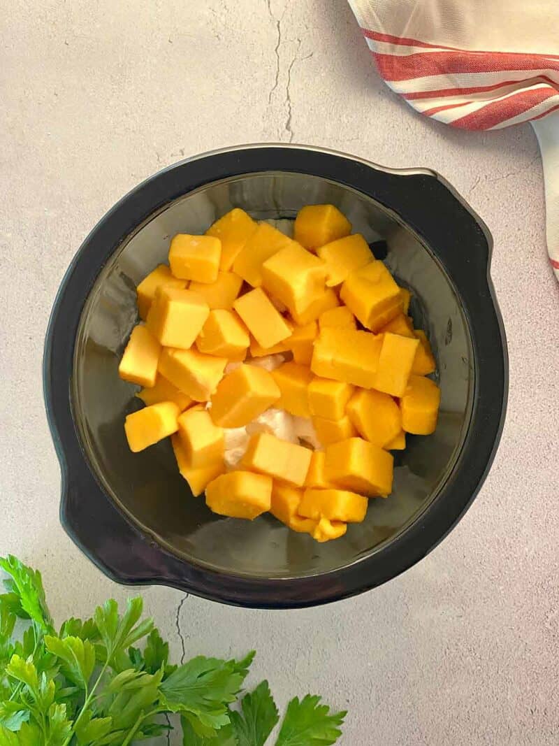 Cubed American processed cheese in a crock pot.