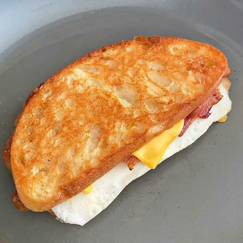 A golden brown cooked egg and cheese sandwich in a skillet.