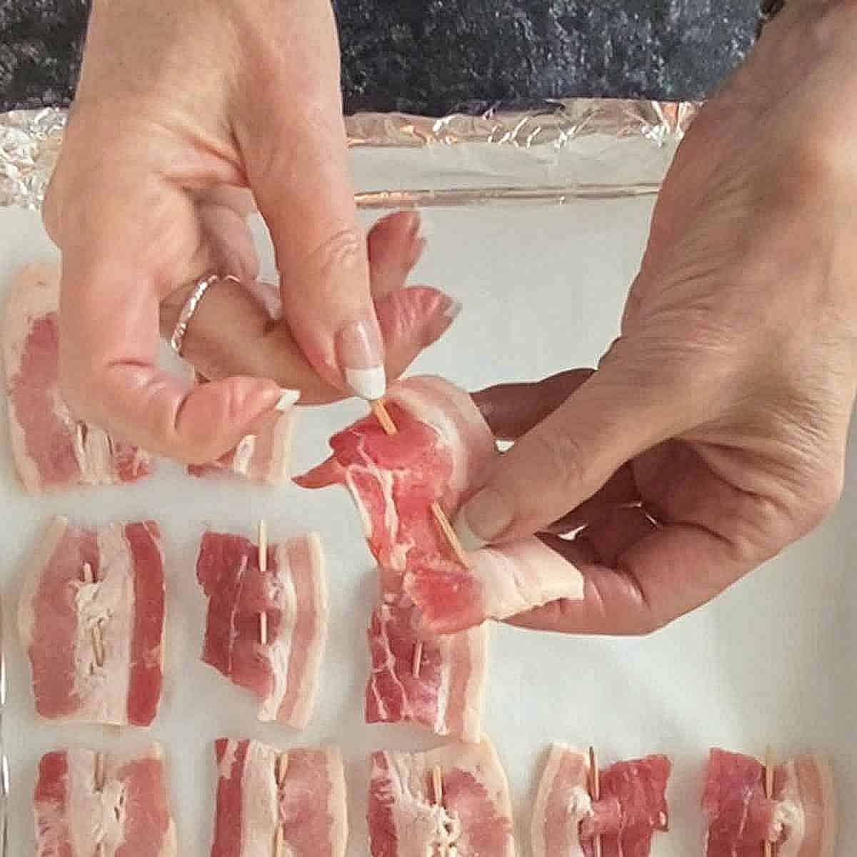 Threading a toothpick through a piece of bacon.