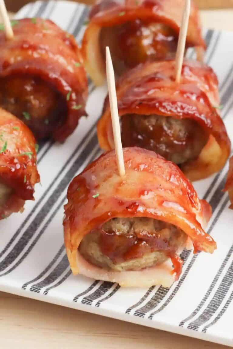 A half dozen bacon wrapped meatballs on a serving dish.