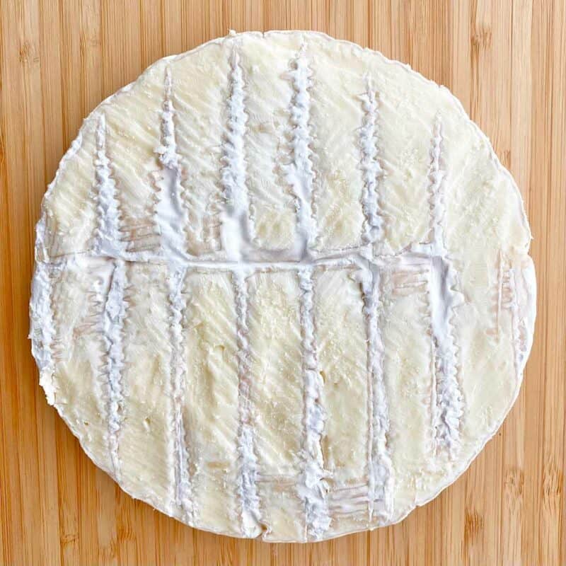 A one-pound wheel of Brie Cheese with the top layer of rind trimmed off.