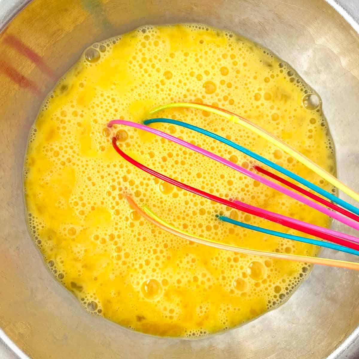 Beating eggs with a whisk in a mixing bowl.