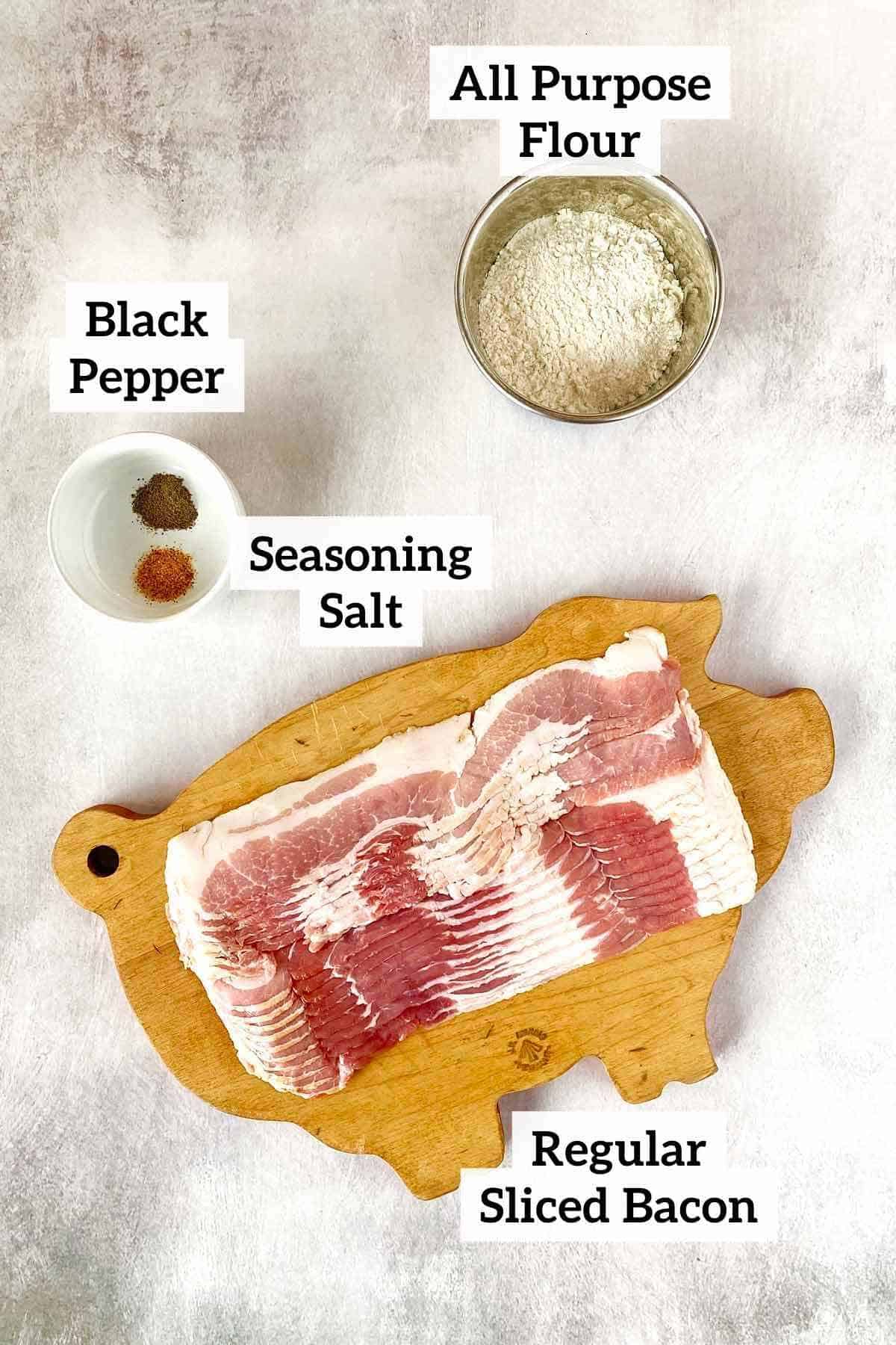 A bowl of flour, a dish with black pepper and seasoning salt, and a cutting board with raw bacon.
