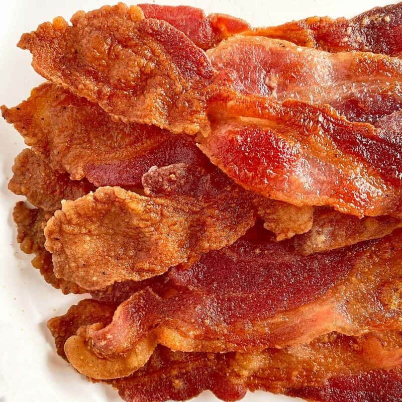 A pile of bacon cooked with flour on a white serving plate.