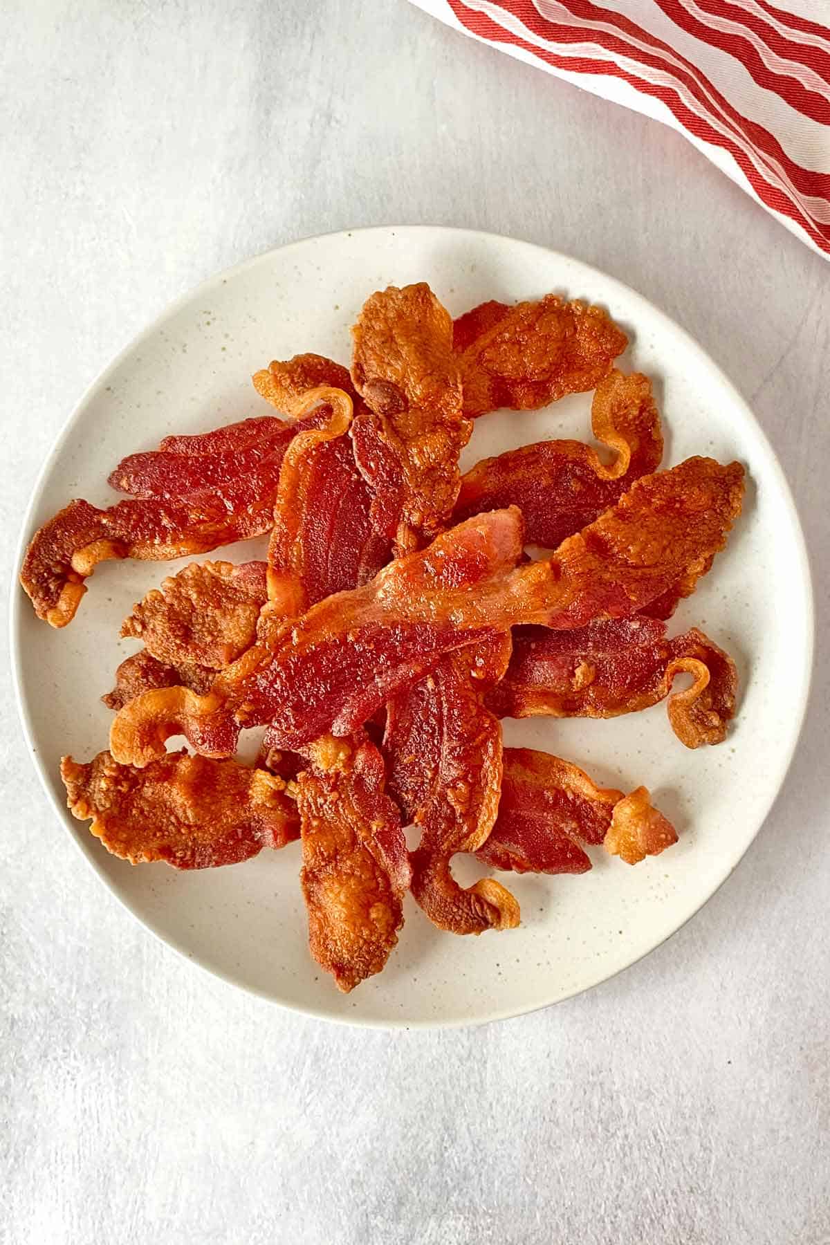 A pile of golden brown cooked flour-coated bacon on a white serving plate.