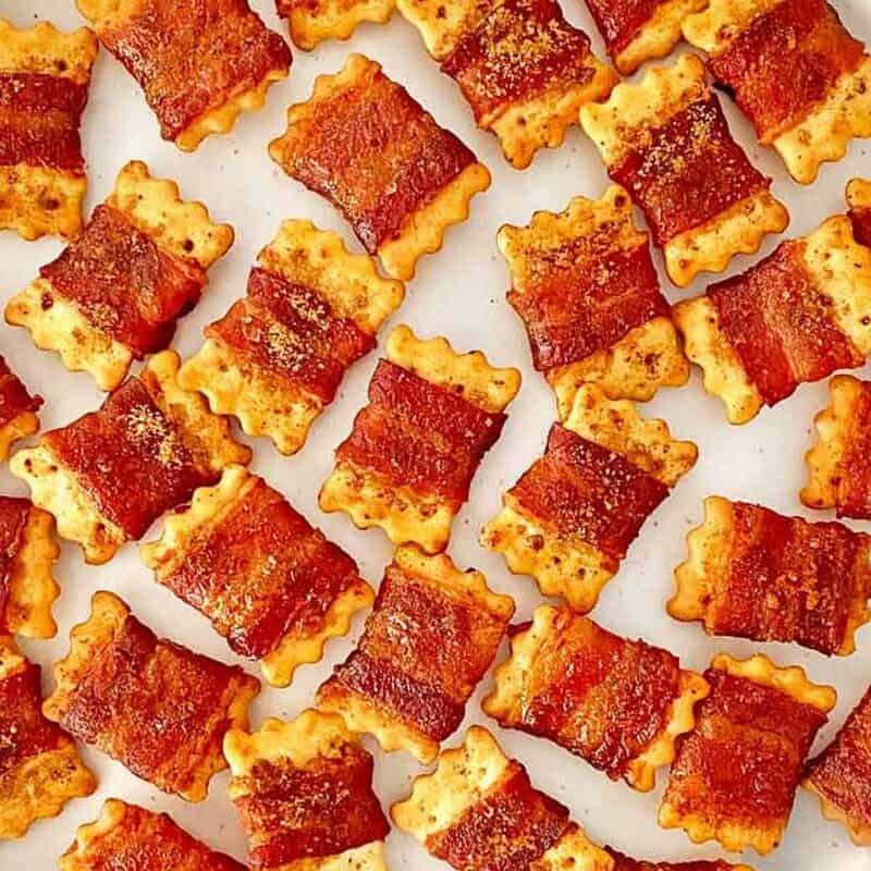 Candied bacon wrapped crackers arranged on a white serving tray.