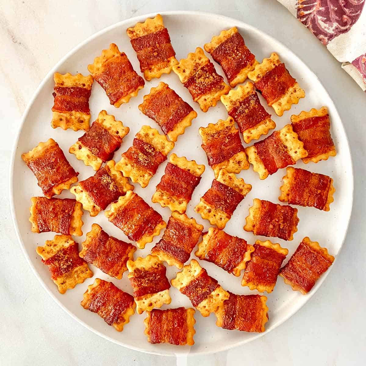 A serving platter filled with brown sugar pepper glazed bacon wrapped crackers.