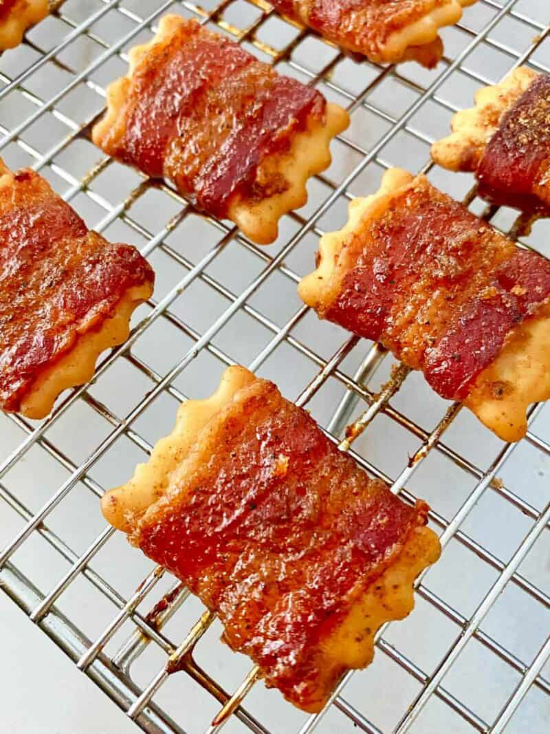 Hot candied bacon wrapped crackers cooling on a wire baking rack.